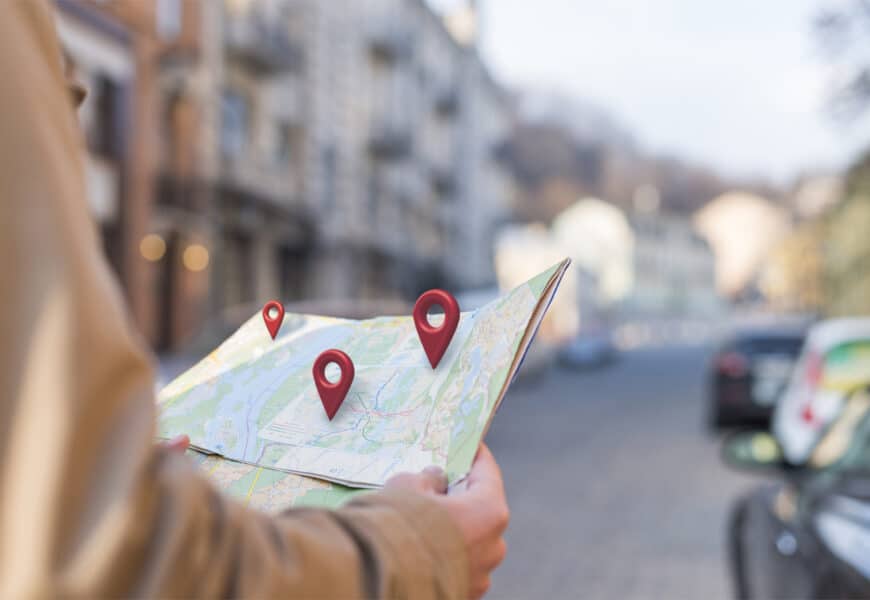 Homme regardant une carte avec des pins de type google map affichés dessus symbolisant le référencement local